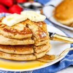 Picture of white plate with stack of brown sugar pancakes with two slabs of butter on top and a gold fork with syrup on the side.