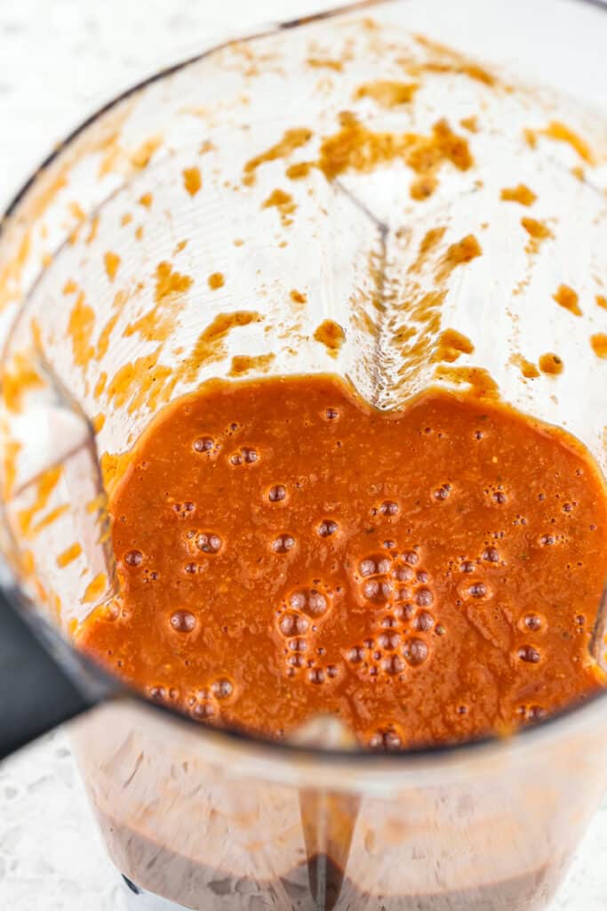 Blender of red sauce on a white backdrop.