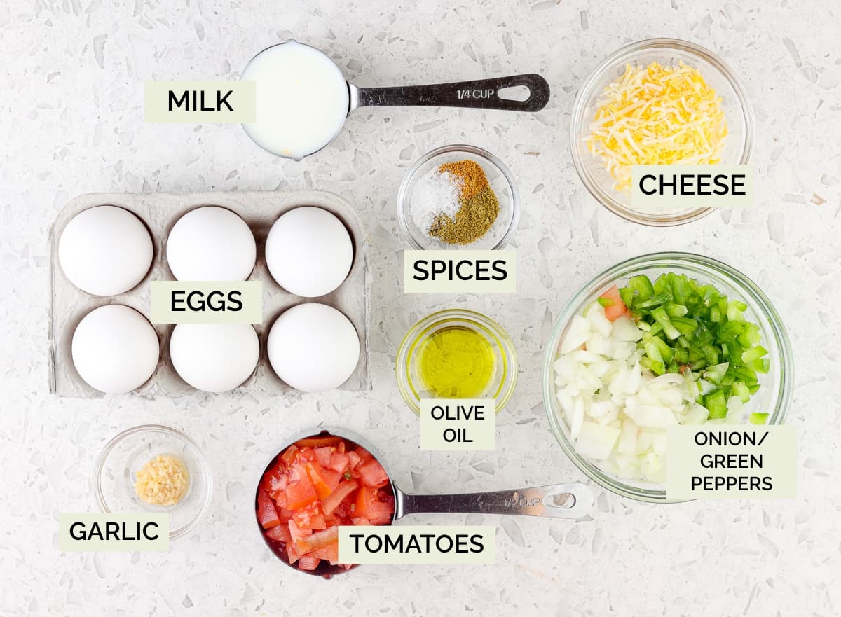 White marble background with picture of eggs, cheese, veggies, and spices in bowls.