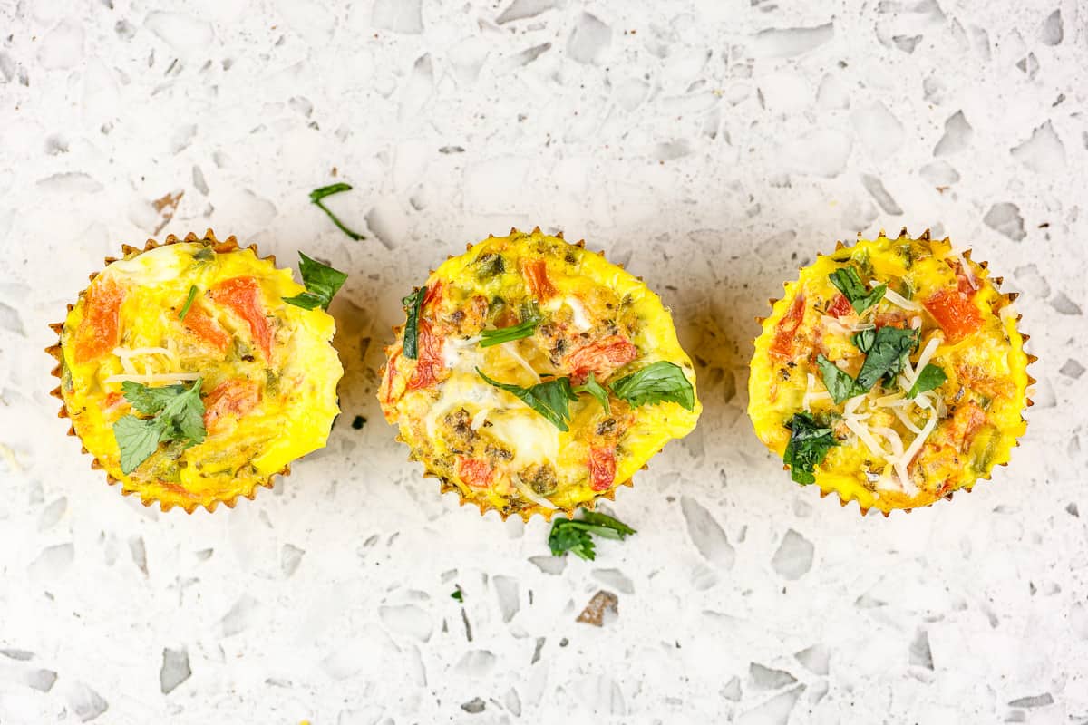 Picture of white marble backdrop with 3 veggie frittata muffins in a row.