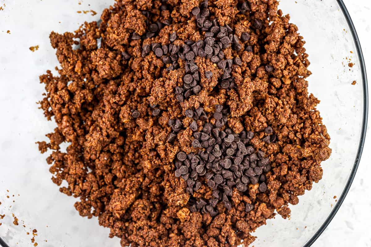 Image of cocoa peanut butter cookie dough with mini chocolate chips on top against a white backdrop.