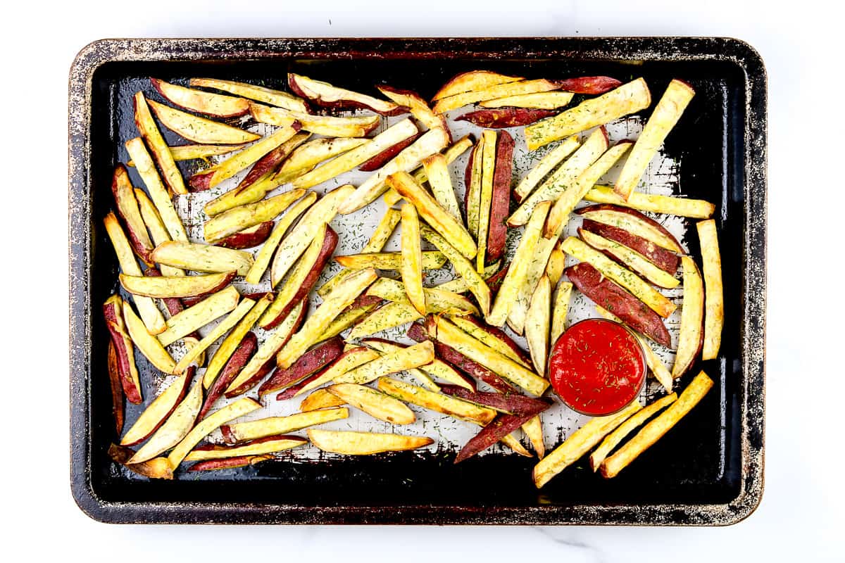 Image of French fries on a baking sheet with ketchup.