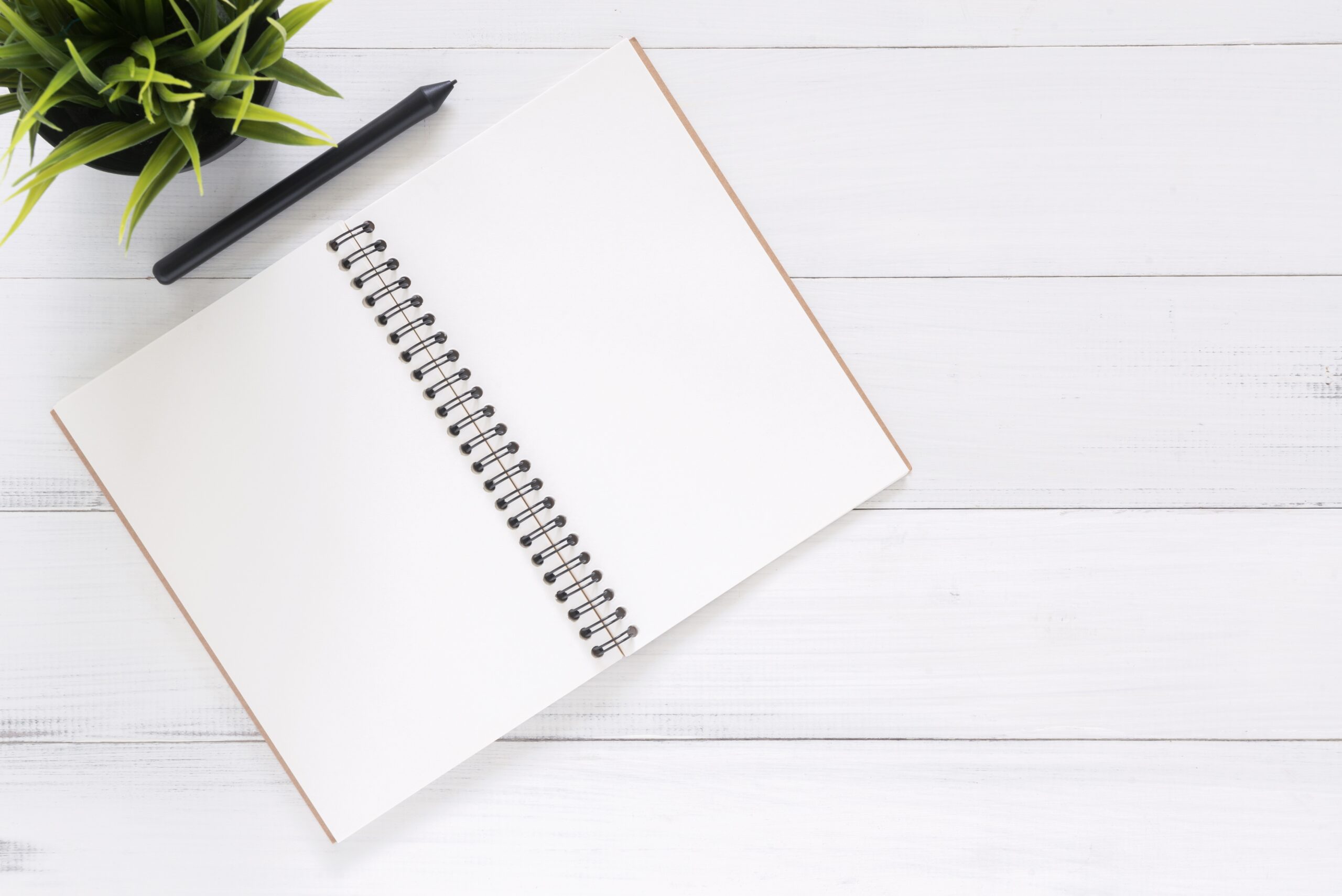 Notepad on white backdrop with pen on top.