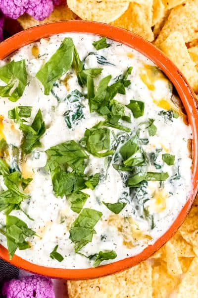 Image of plated spinach dip with chips and cauliflower around it.
