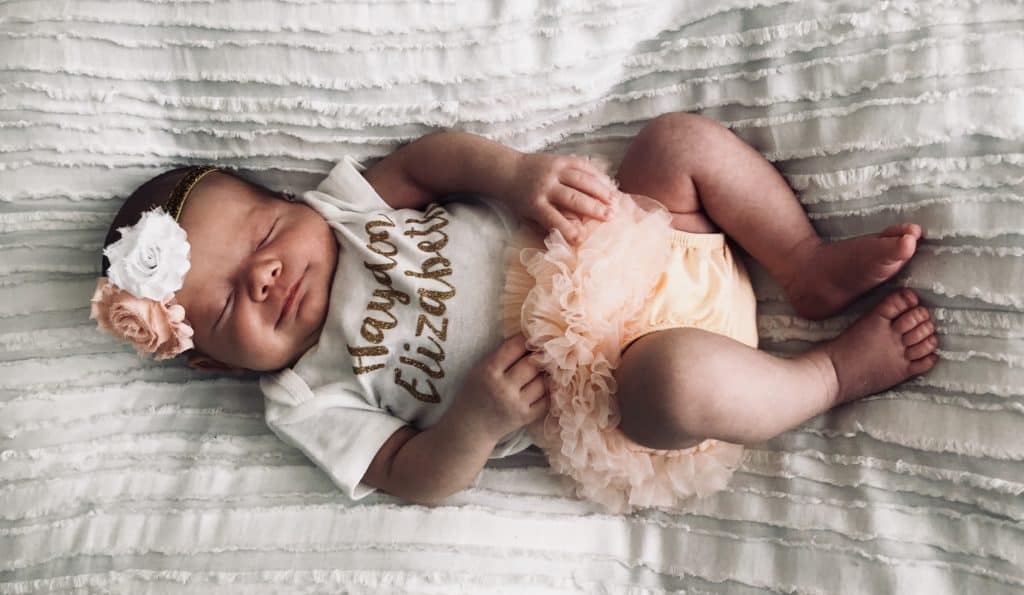 Picture of baby girl wearing newborn outfit 2 weeks old.