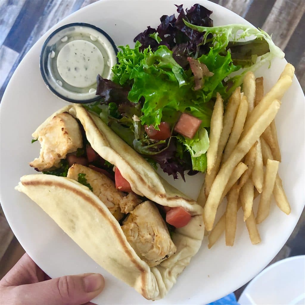 Image of pita bread with chicken, fries and salad.