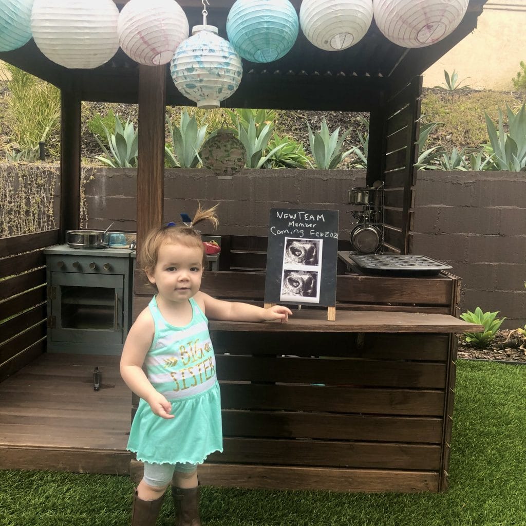 Image of toddler announcing becoming a big sister with ultrasound photo.