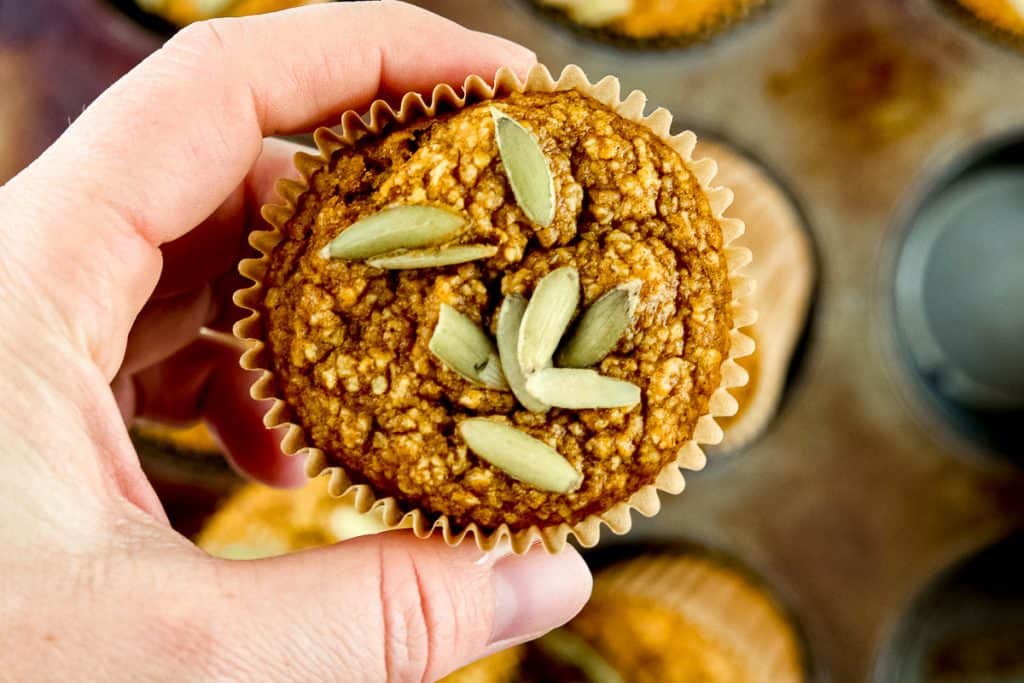 Holding a single muffin with pumpkin seeds on top.