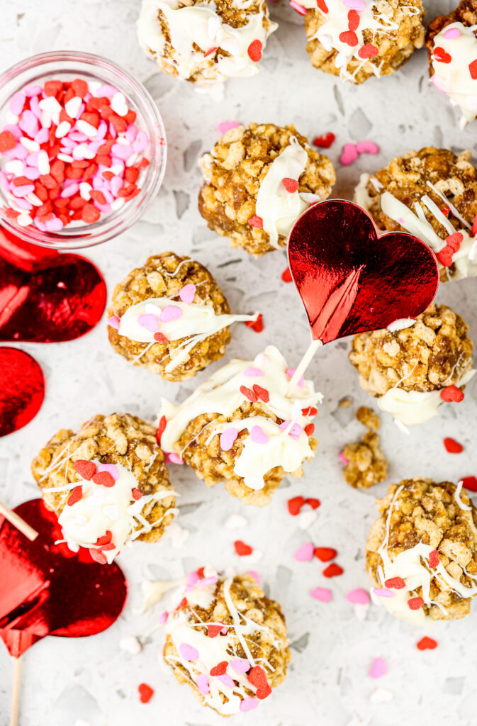 White marble tile with cereal cake pops covered in white chocolate and red sprinkles.