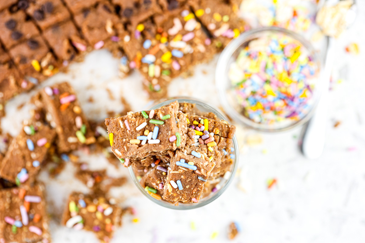 White backdrop with light brown chickpea cookie dough with rainbow sprinkles on top.
