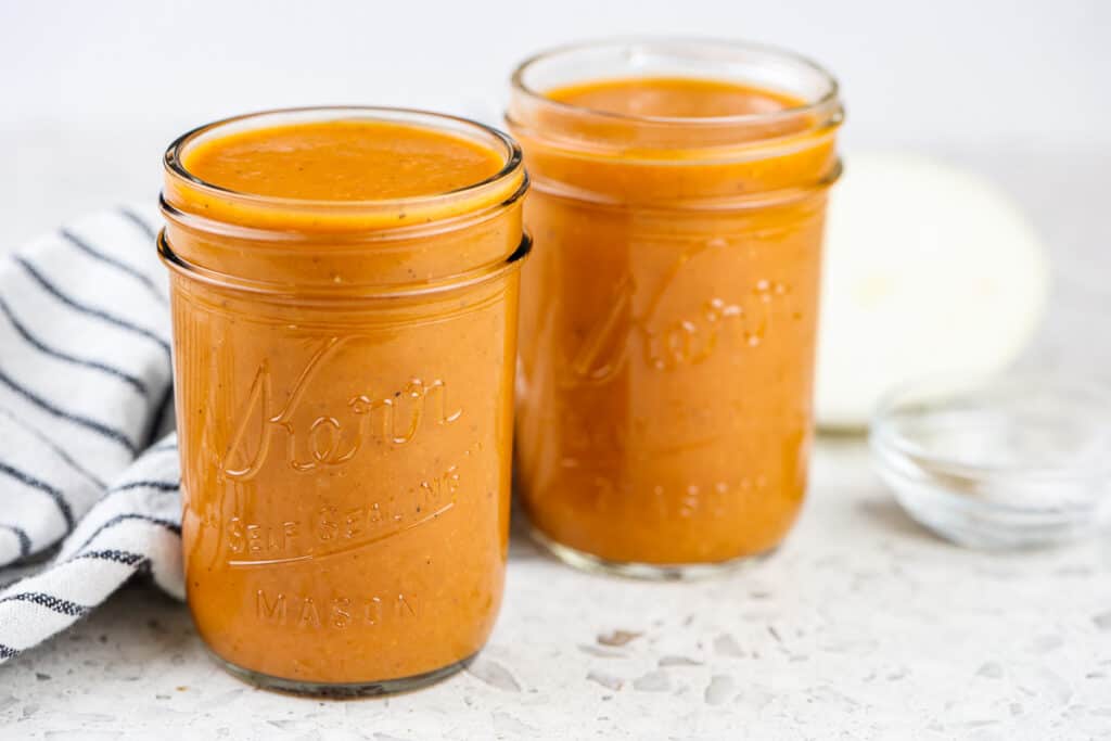 White marble backdrop with two mason jars of habanero bbq sauce.