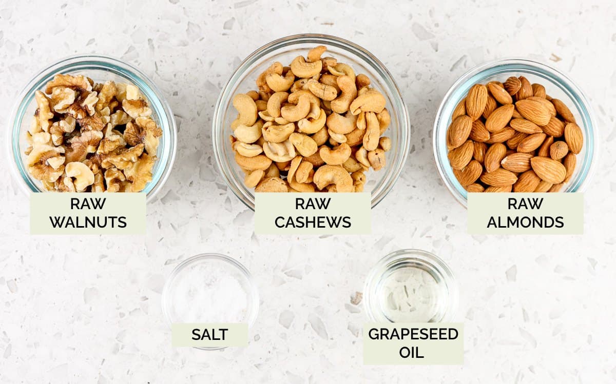 White backdrop with 3 glass bowls of nuts with green text overlay to show how to make roasted mixed nuts.