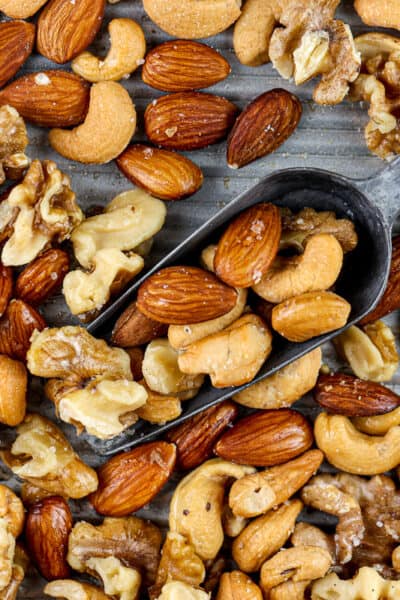 Silver baking sheet covered with roasted cashews, almonds and walnuts with a metal serving handle in the center.