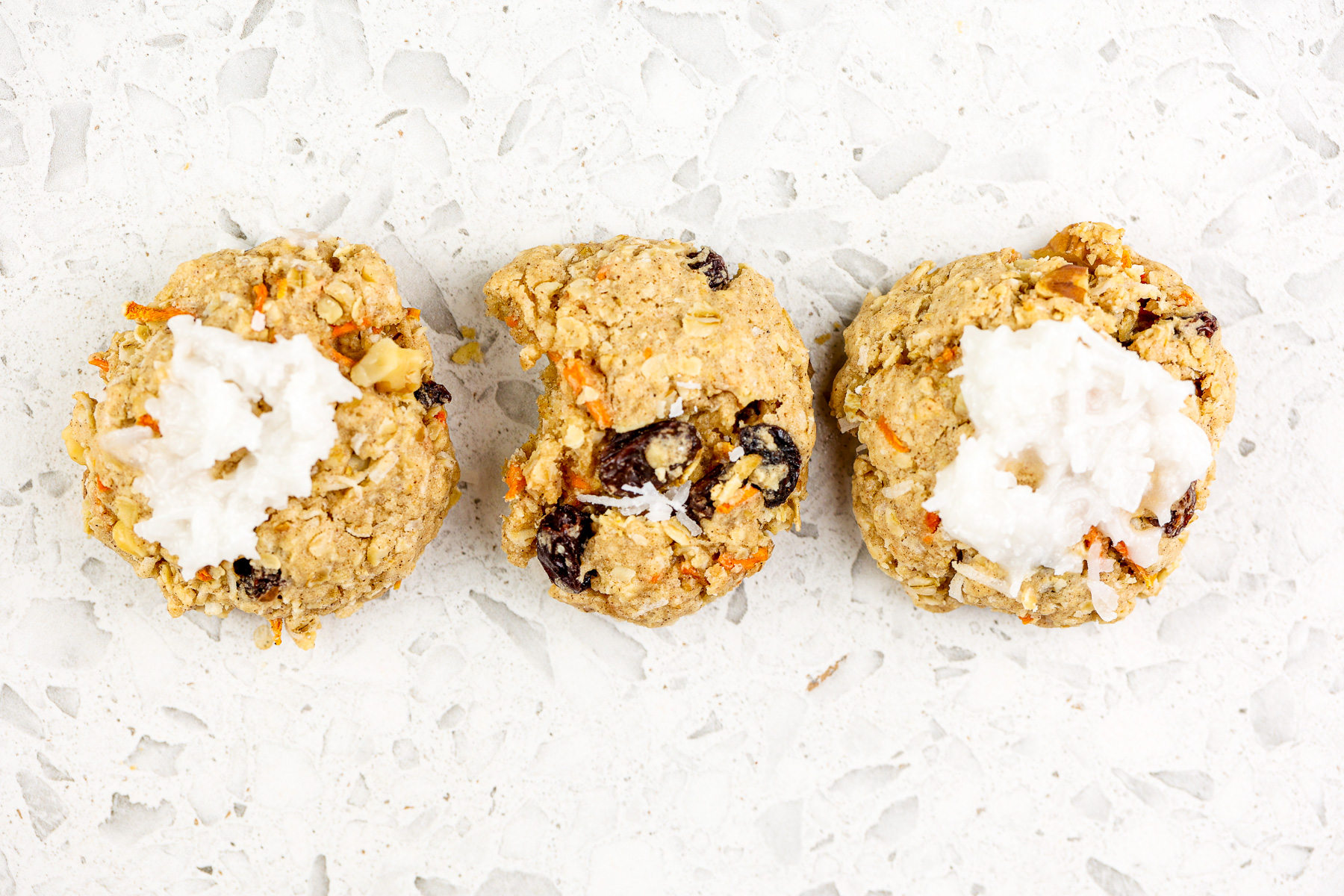 White marble backdrop with single cookie on top with one bite out of it.