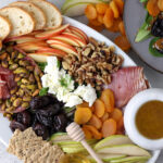 Charcuterie Salad on a plate with a honey comb stick and container of dressing.